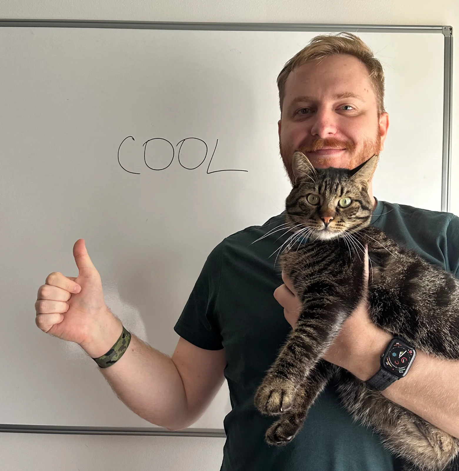 Dmitry Belianin holding a cat and giving a thumbs up, with the word 
